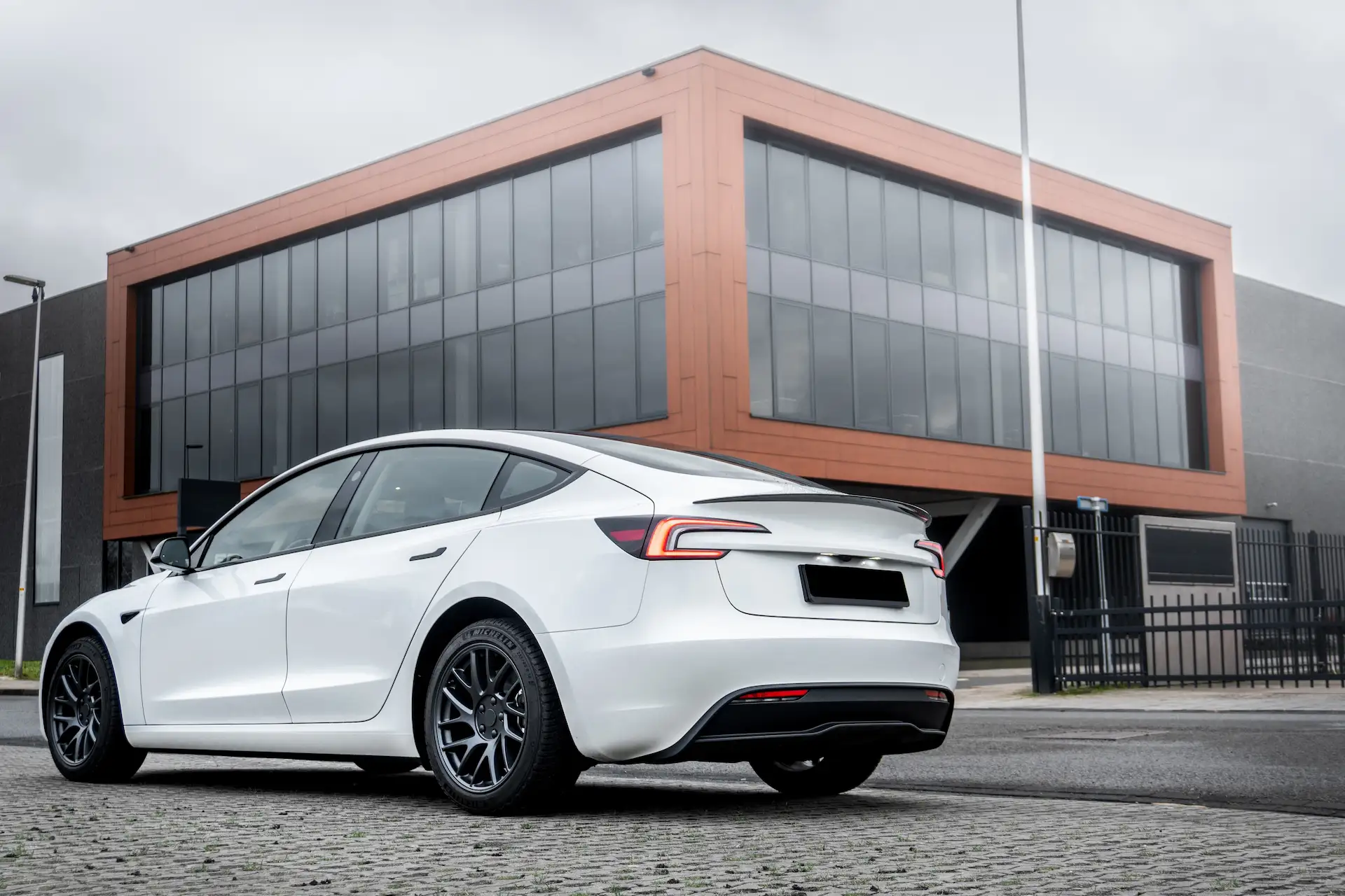 Weißer Tesla Model 3 Highland in der Heckansicht mit Spoiler und schwarzen Felgen